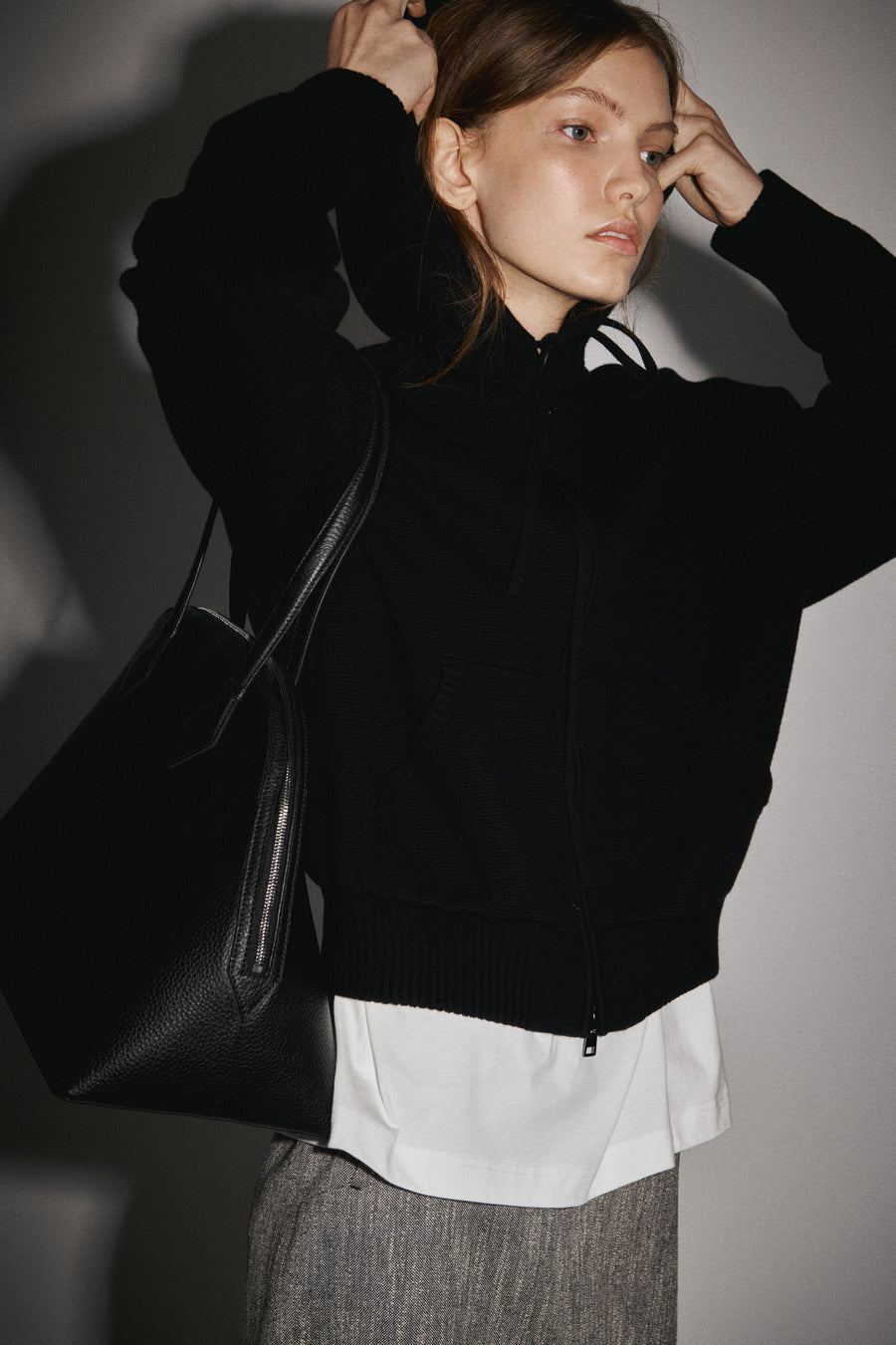 Olisha wears the the Samuel Knit Hoodie over the Persey Top with the Innes Skirt & Harnick Bag.