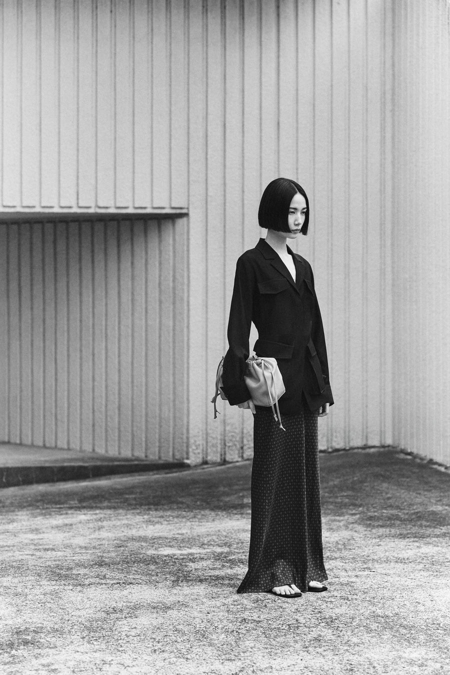 Tsugumi wears the Frank Jacket with the Riva Skirt, Clara Sandal and Tobey Bag in Greige.