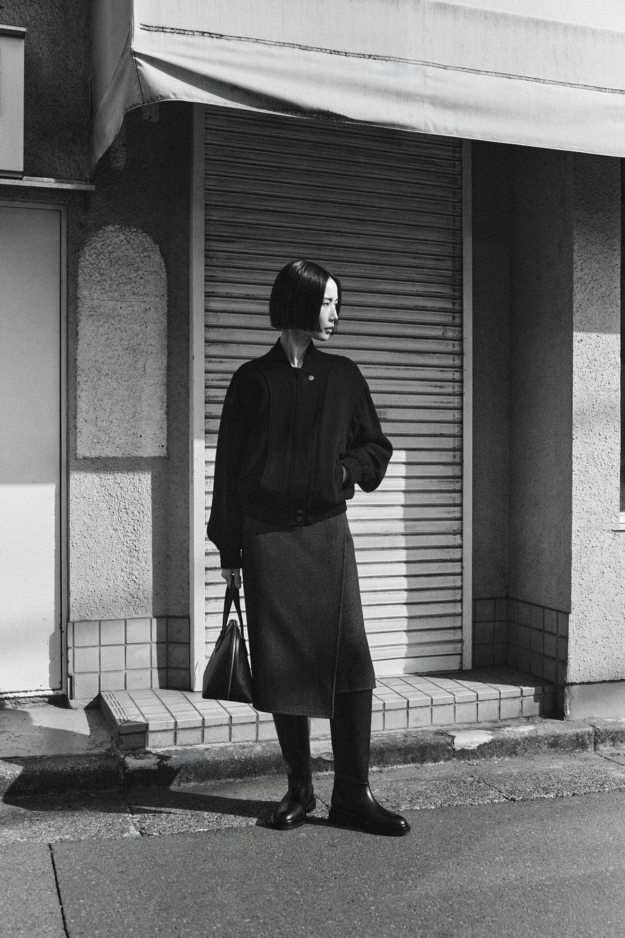 Tsugumi wears the Giles Bomber Jacket and Roche Skirt with the Jude Knee High Boot and Harnick Top Handle Bag. 